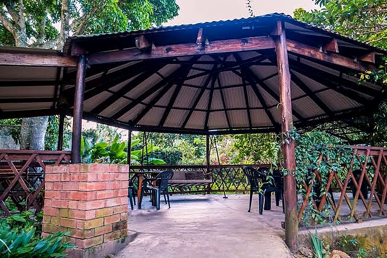 Thatched lapa with seating and a braai area in the gardens